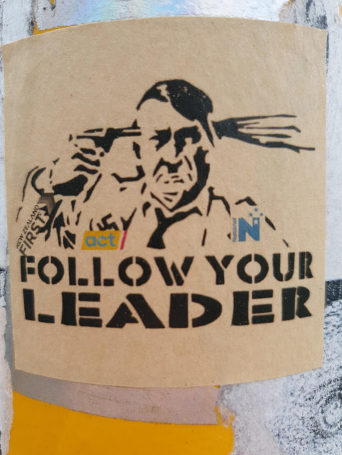 Sticker of Hitler committing suicide with large text saying "FOLLOW YOUR LEADER". Hitler's clothing includes the logos of the three right-wing political parties running the New Zealand government (National, Act, NZ First).