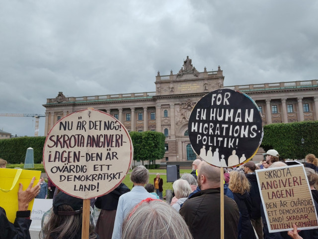 Skyltar mot angiverilagen. Riksdagshuset i bakgrunden.