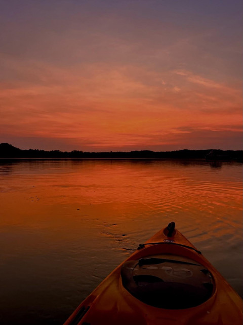 An unshared photo from last year because I am months away from being cleared to kayak. 
You sit in a papaya colored kayak whose front tip is visible on a calm lake late into a deep red summer sunset. Time to paddle home before it gets too dark.