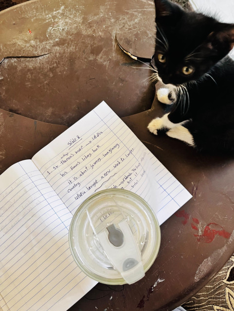 A table with small pieces of paper, a notebook, and a glass of water.