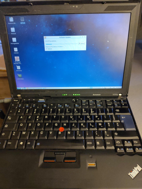 Photo of a small black laptop with a screen showing the desktop of an old version of Ubuntu and a very nice keyboard with a red trackpoint