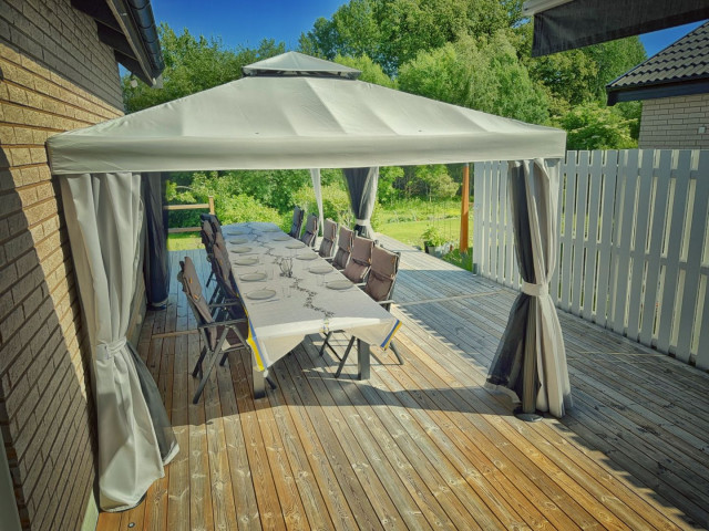 Our new outdoor seating area, with a long table, 12 chairs, under a pavilion which stands on our decking.