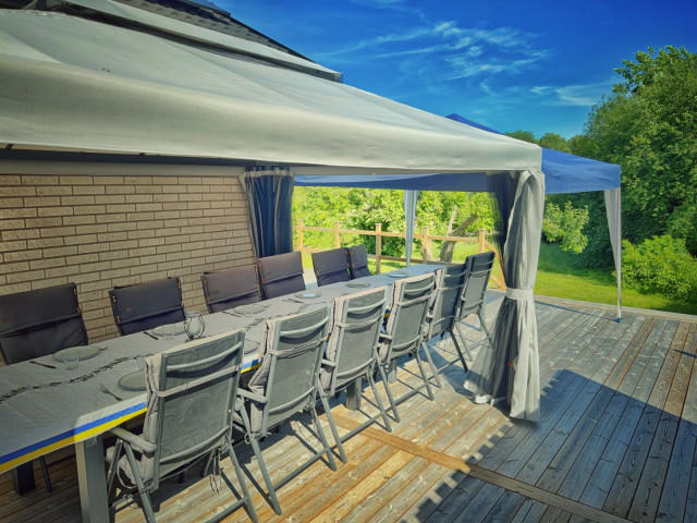 Our new outdoor seating area, with a long table, 12 chairs, under a pavilion which stands on our decking.