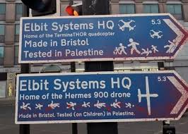 Two fake road signs pointing towards "Elbit Systems HQ"

Top one has the following additional text "Home of the TerminaTHOR quadcopter, Made in Bristol, Tested in Palestine"

Lower one has the following additional text "Home of the Hermes 900 drone, Made in Bristol, Tested (on children) in Palestine"

Both signs show stick persons running and falling with quadcopters and drones.