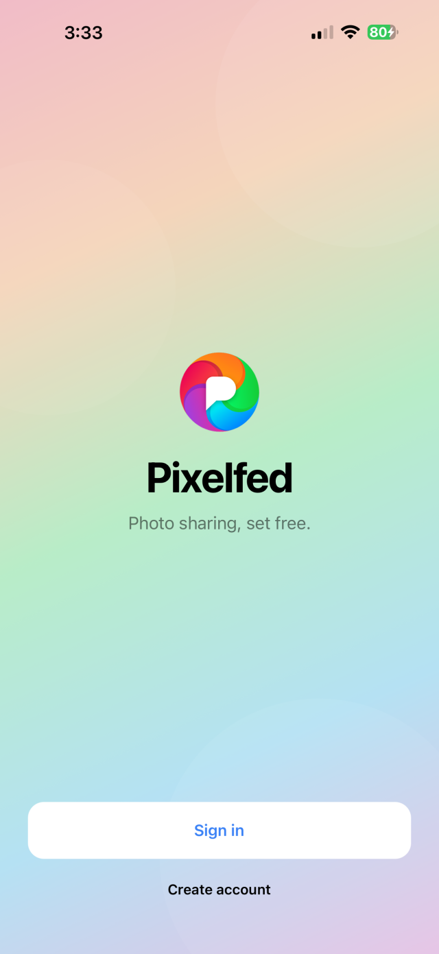 Screenshot of the new Pixelfed mobile app landing screen on iOS with a gradient background consisting of the logo colours with the Pixelfed logo and text below that says "Pixelfed" and below that in smaller text "Photo sharing, set free." with a Sign in and Create account button at the bottom of the screen