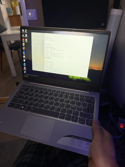 Kuvassa auki lenovon kannettava tietokone, jota kuvaajaa pitää kädessään.