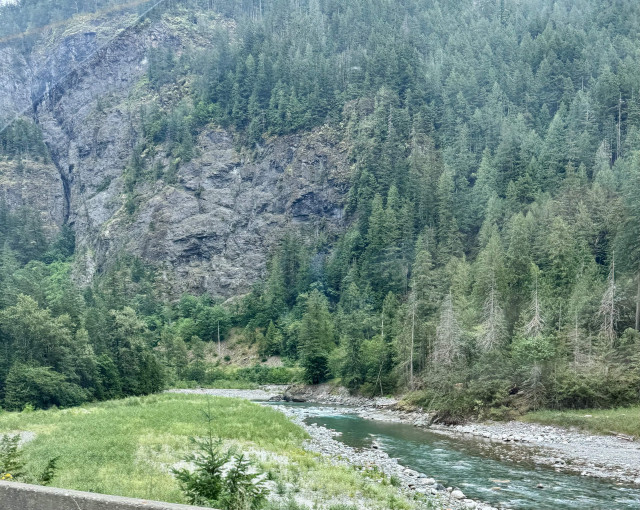 River by a lush, rocky forest mountain 
