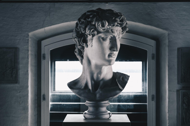 Sculpture of David's head on a piedestal in a room.