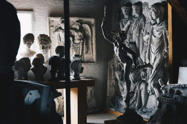 A collection of sculptures in a dark room with light coming from a window.