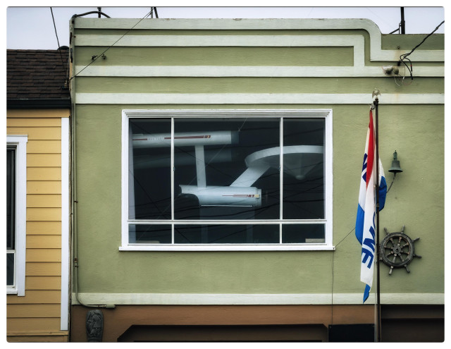 A 14-foot model of the original Star Trek Enterprise NCC 1701 hangs in the second story picture window of a house on 46th Avenue in the Outer Sunset. The Enterprise boldly fills up the window, stretching from one side to the other and then some.

Other details: the house is painted sage green and has deco trim on the facade. There's a flagpole with some kind of red white and blue flag hanging out front. On the left there's a yellow painted house. And most importantly, fuck David Ellison.