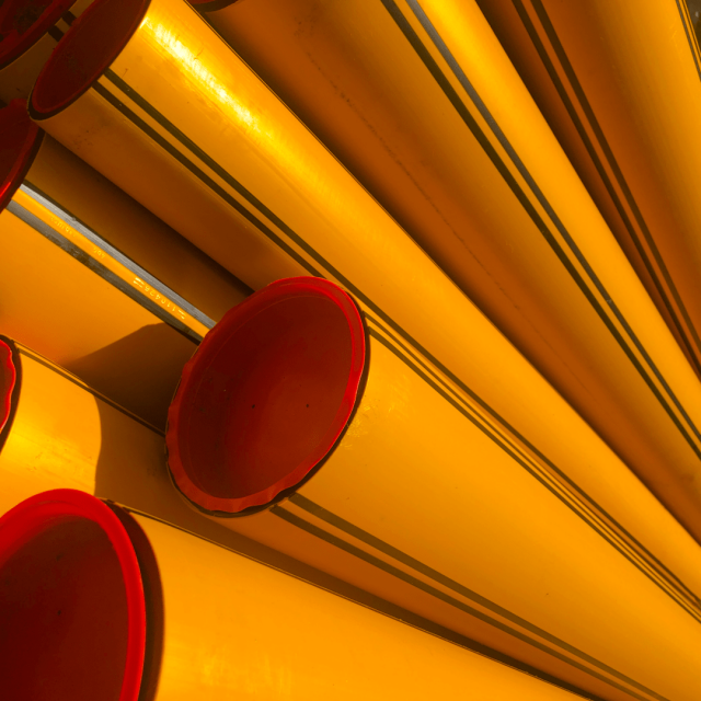 Detail of bright yellow/orange PVC pipes with bright red caps on the ends.