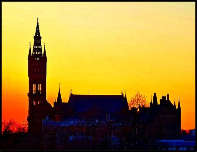The gothic Victorian buildings of Glasgow University silhouetted against a sunset.