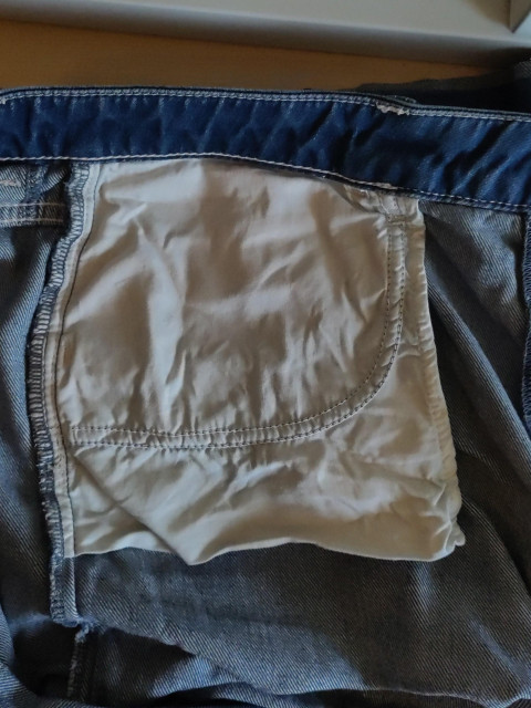 The insides of a pair of yeans, showing the ridiculously small left front pocket.