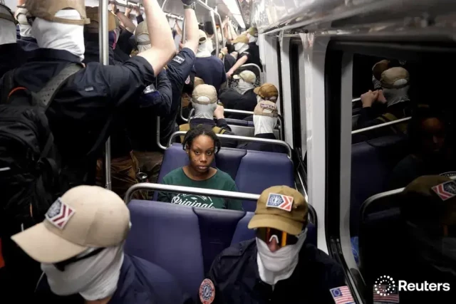 Black woman sitting on a bus, surrounded by white (fascist) masked men.