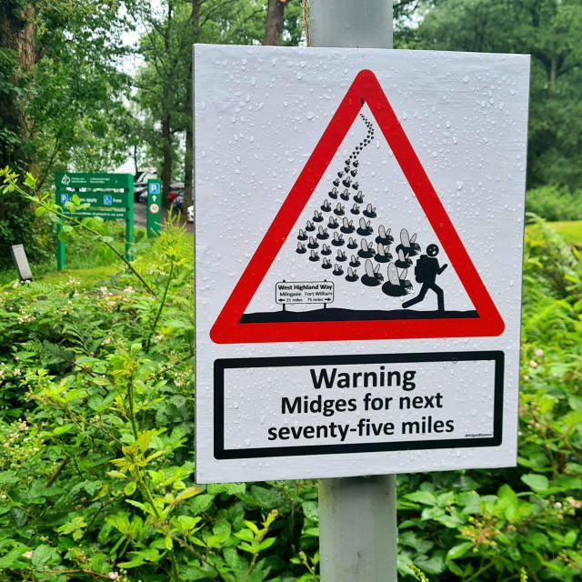 A road sign showibg a person with a backpack being pursued by a horde of midges. Below are the words Warning: Midges for next seventy-five miles.