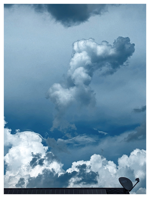 A dramatic sky filled with fluffy white and gray clouds, including a tall, irregular cloud formation in the center. At the bottom, a rooftop with solar panels and a satellite dish, is partly visible against the sky