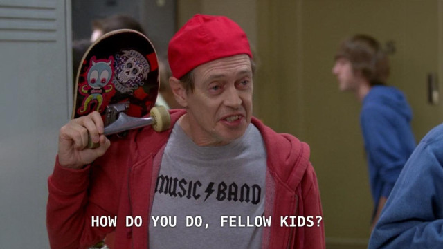 A middle-aged Steve Buscemi in 30 Rock as an undercover private investigator at a high school, dressed in a Music Band t-shirt in the style of AC/DC, a red hoodie, a red cap on backwards, and carrying a skateboard on his shoulder.