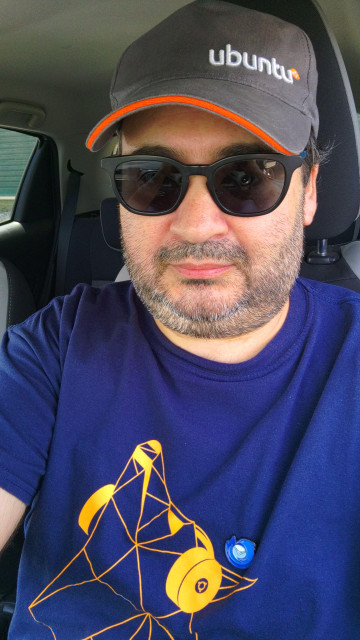 Selfie while wearing an Ubuntu hat, an Ubuntu Disco Dingo tshirt and a Thundetbird pin.