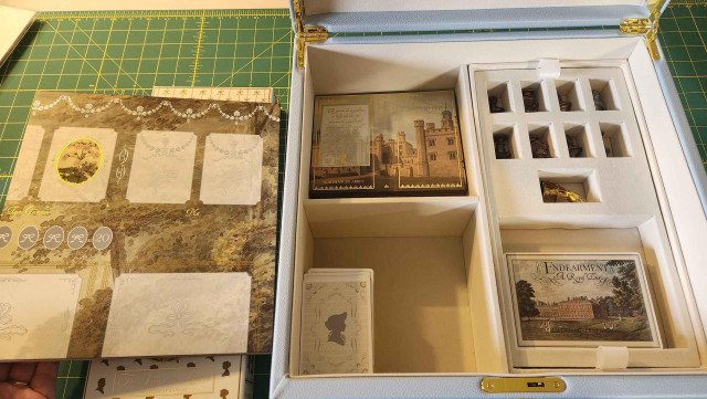 The box opened, showing small figures for player pieces, and cards for the characters, setting, etc. The cards are very ornate and have gold gilt.