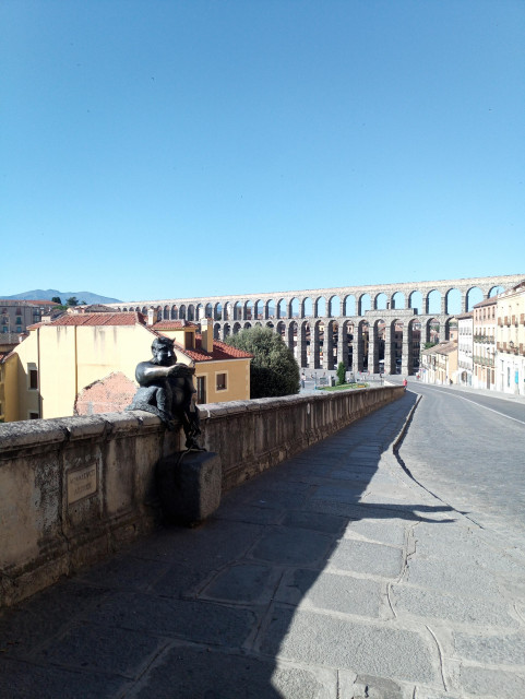 My photo of a bronze devil statue sitting on a wall with a mobile taking a selfie with the aqueduct behind.