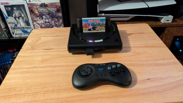 A picture of an Analogue Mega SG with a copy of Monopoly in the system, and a wireless controller.