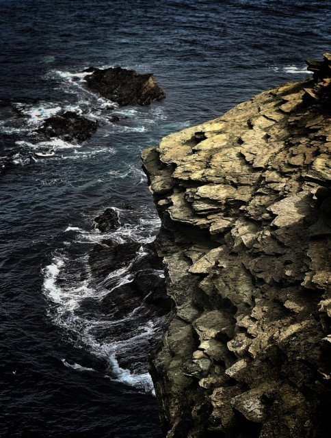 Rugged orange rock strata jutting out into sea.