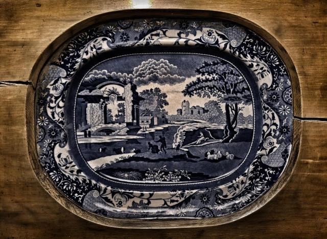 Blue china plate set in wooden panel.