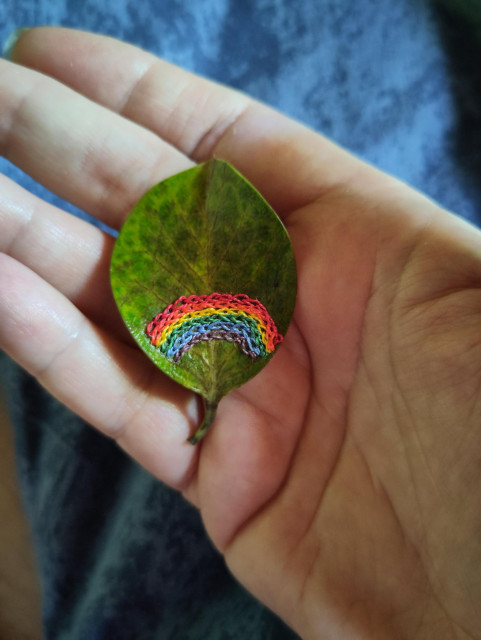 Une petite feuille dans ma main, avec un arc en ciel brodé au point de chaînette 