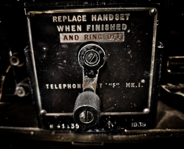 Tarnished metal windup lever for old phone.