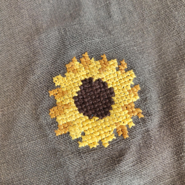 Sunflower cross stitch on olive linen material. 