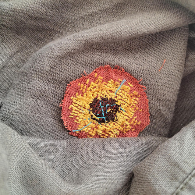 Back of the cross stitch with a brown linen patch. 