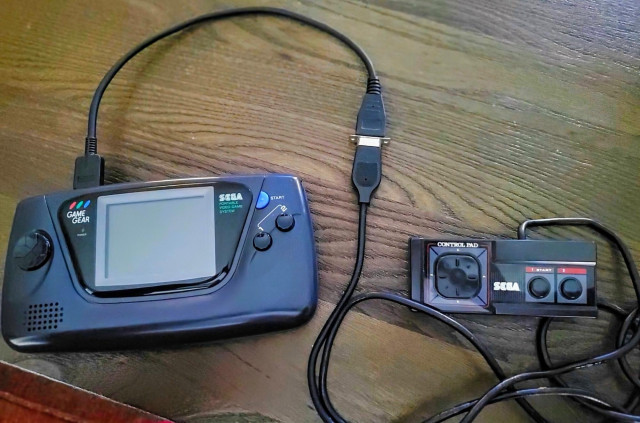 My Game Gear on a table with a Master System controller connected to the EXT port through a short converter
