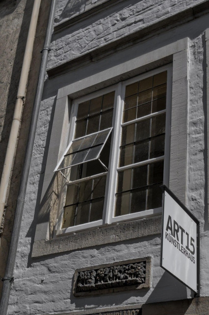 Fassade eines Gebäudes mit einem geöffneten Fenster und einem Schild mit der Aufschrift 'ART15 KÜNSTLERHAUS'