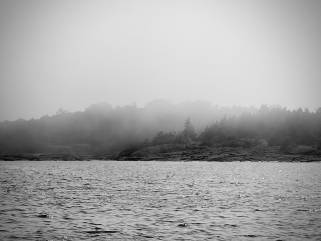 Black and white photo of 2 islands in the sea with fog between them