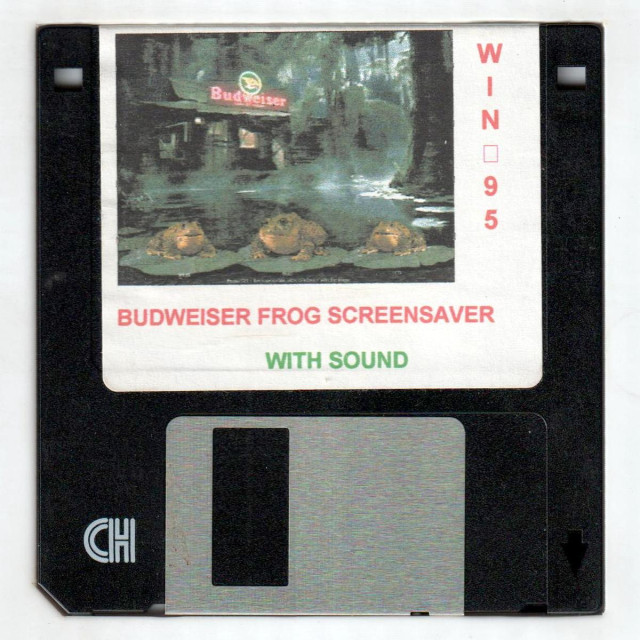 A scan of the disk for one of the most important pieces of software to ever exist: BUDWEISER FROG SCREENSAVER WITH SOUND for WIN[broken character]95! It's a black floppy disk with a brushed metal shutter, and a very cheaply-produced, inkjet-printed label depicting three bullfrogs sitting on lillypads in a swamp, from which rises a bar/pub with a giant neon Budweiser beer sign on. 

Anyway, down in the bottom left is a symbol that's on every high-density 3½" floppy disk, whether embossed into the plastic, or as in this case, silkscreened on. From this angle and due to the styling of the letters, it looks like "CH".

But the designers of the 3½" floppy disk intended disks to be viewed with the shutter on top and the label at the bottom. You'll even find commercial disks labeled that way on occasion (IIRC, Microsoft did it *sometimes*). From that point of view, the symbol looks more like what it's supposed to depict: HD, for high-density.

But for the most part, the people spoke: the label goes on top, ya dinguses.
