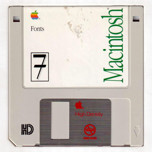 Another scan of a floppy disk, this one a beige-y off-white, again with a brushed-metal shutter. The shutter is fancily silkscreened in red: an Apple logo, the words High Density, and an icon depicting a floppy drive with a circle and a line through it, with "400k/800k" written below (early Macs used single- and double-sided double-density floppy drives, which couldn't read newer high-density disks). The label is professionally created this time, with a white background, the word "Macintosh" written up the right side in green Apple Garamond, a multi-color Apple logo in the top left, the disk title ("Fonts") below that, and a large "7" in the bottom right in a funky 90s font, as this disk belonged to the new System 7.0.

But what's really impressive here is that the standard "HD" logo in the bottom left has been rotated so that it reads correctly when the disk is viewed the right way up!