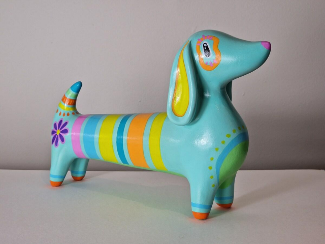 Large ornament of a mint green sausage dog covered in coloureful stripes, patterns, and flowers