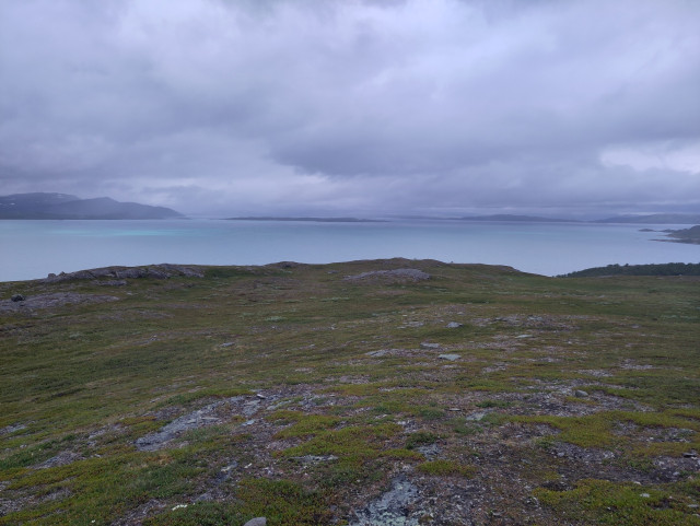A large lake from above, with low clouds. A big island can be seen in the distance.