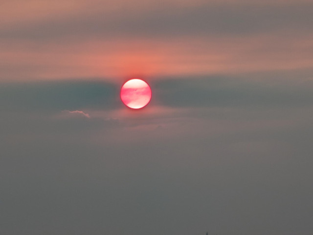 Soleil rouge dans des nuages de fumées 