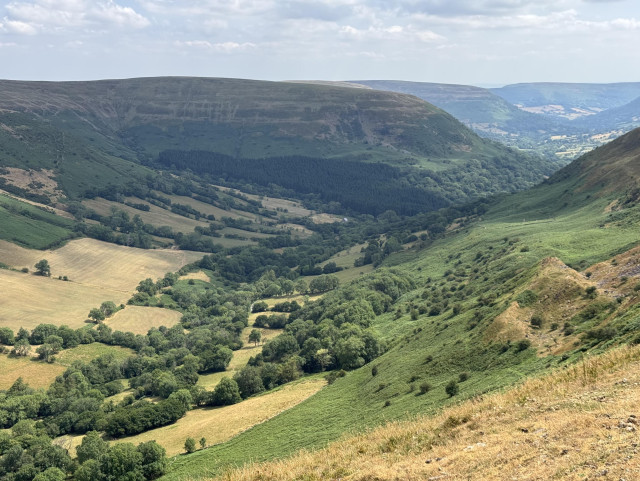 View towards the top of the steep sided Gospel Pass. The tops of the mountains here are greener and the valley floor is dotted with trees. 