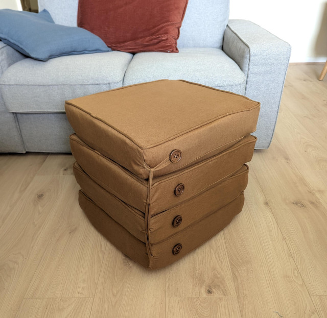 A stack of four square golden-brown cushions, held together by a line of loops and buttons running up the side.