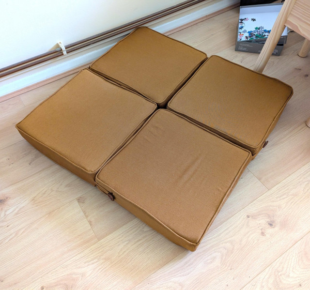 The same four cushions laid out in a square on the ground, buttoned together at the corners.