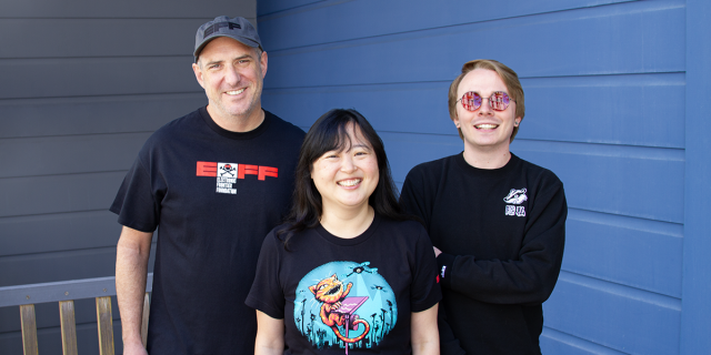 Three EFF staffers wearing new swag. EFF's DEF CON 34 t-shirt, Claw Back t-shirt, and Privacy Badger Crewneck