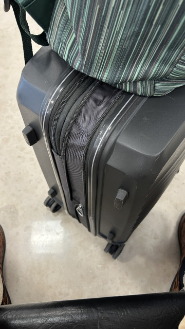 The suitcase with the accordion expansion unzipped, with my cool $5 backpack on top