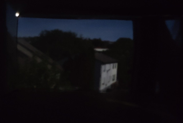 Testbild, reingezoomt und gedreht. Man sieht deutlich den Himmel, Bäume, und ein Nachbarhaus. 
