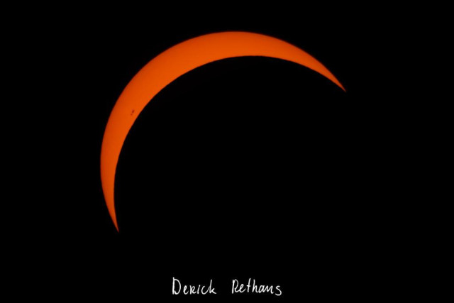 A black background, with yellow arch. The arch is a ~20% crescent in the top-left. Just on the limp there are a few dark spots visible. 

In the bottom it has "Derick Rethans" in a handwritten-like font.
