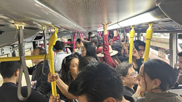 Inside a crowded bus with bright yellow bars for holding on.