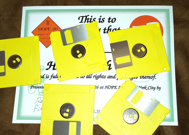 An award certificate of some sort is obscured by a bunch of yellow 3.5 inch floppy disks scattered over most of it.