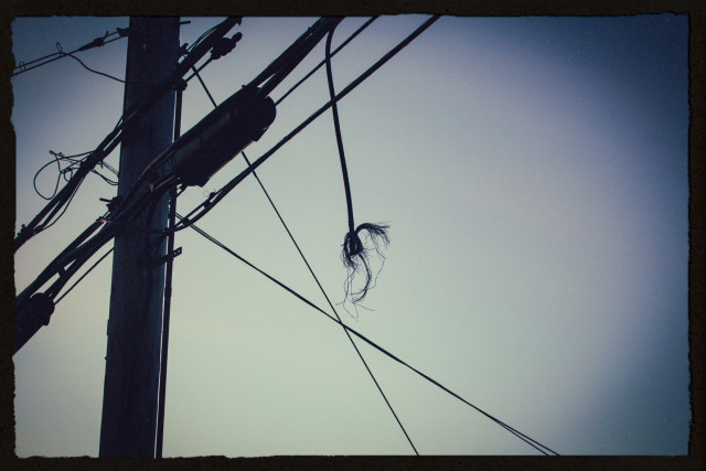 dusk photo of a utility pole with a dangling power line that's been frayed