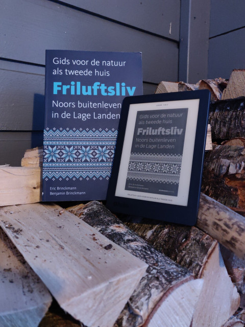 Het boek 'friluftsliv' geposeerd op een houtstapel met een e-reader ernaast, met de cover van hetzelfde boek erop.